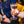 Load image into Gallery viewer, Someone is holding a lychee martini. It looks like they are in a bar. There is someone blurred in the background wearing a blue top and jeans, and sitting on a bright yellow chair.
